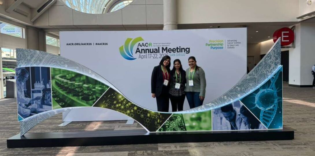Three women gathered together in front of a decorative structure at the AACR Annual Meeting