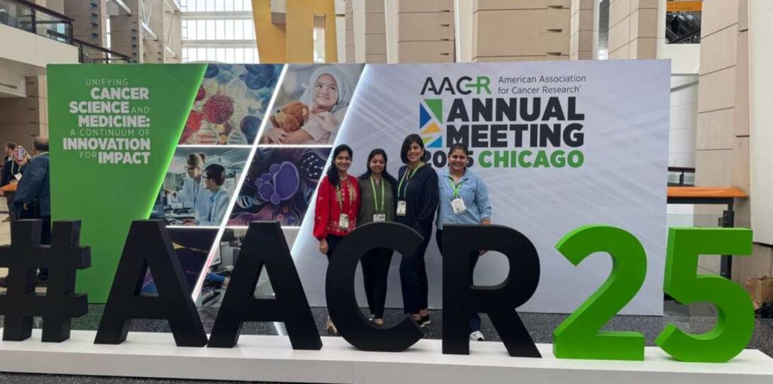 4 women gathered behind a #AACR25 structure